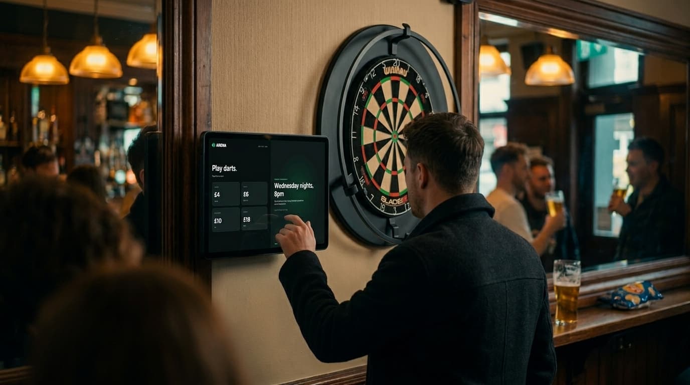 A customer using the SportsArena Terminal next to the dartboard in a British pub.